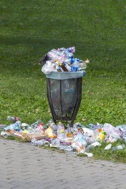 Etrafı çöplerle dolu bir çöp tenekesi.