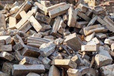 Yıkılmış tarihi binaların yıkıntıları ve tuğla bir çitin arkasında inşaat malzemeleri..