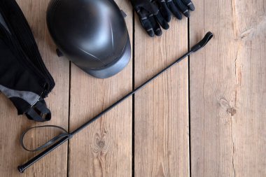 At bakımı için ekipman ve metin için kopyalama alanı: miğfer, kırbaç, eldivenler, dizgin, ahşap arka planda fırçalar