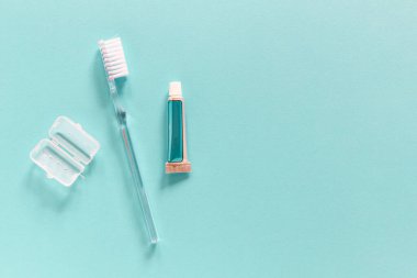Flatlay of travel set with single use toothbrush and small paste tube on a blue background with copy space for your text. Morning routine while travelling  concept