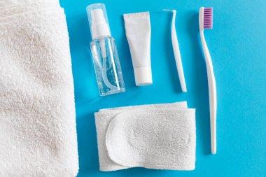 Flatlay of toothbrush and paste, cosmetics and towel on a blue background. Morning routine for women everyday hygiene concept