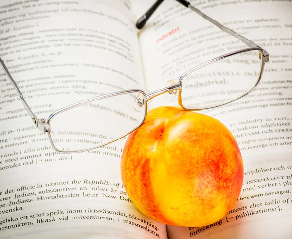 Nectarina e óculos de leitura — Fotografia de Stock