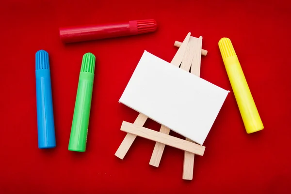 Coloured pens beside easel — Stock Photo, Image