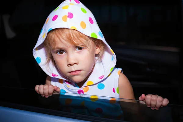 Ledsen liten flicka sitter i bilen nära fönstret — Stockfoto