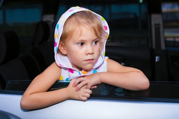 Sad little girl sitting in the car near the window — Stock Photo, Image