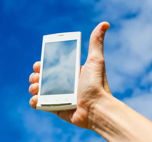 Κινητό τηλέφωνο στο χέρι σε φόντο του ουρανού — Φωτογραφία Αρχείου
