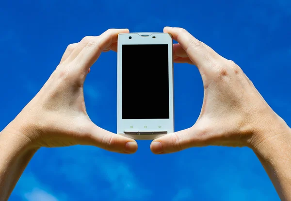 Teléfono móvil en la mano en el fondo del cielo —  Fotos de Stock