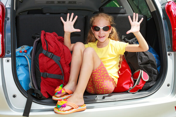 Little girl sitting in the car with backpacks