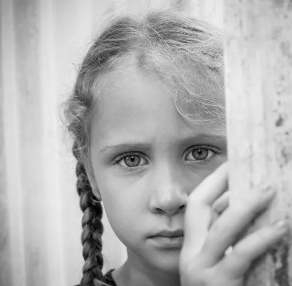Ledsen liten flicka på bakgrund av en vägg — Stockfoto