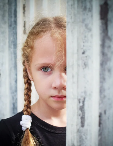 Sad little girl on background the wall — Stock Photo, Image