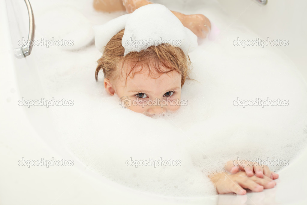 Cute four year old girl taking a relaxing bath with foam