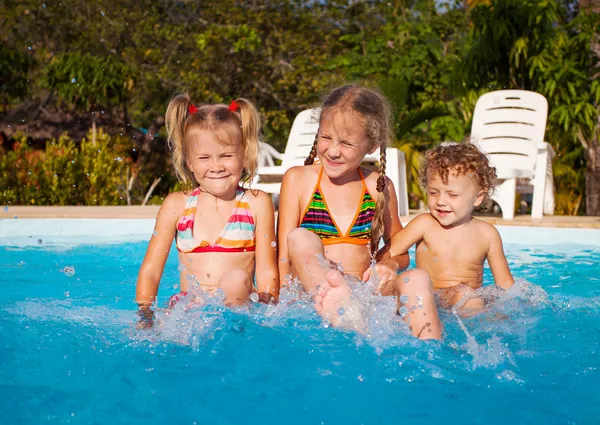 Dos niñas y un niño jugando en la piscina —  Fotos de Stock