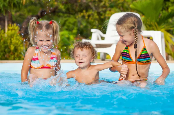 Dos niñas y un niño jugando en la piscina —  Fotos de Stock