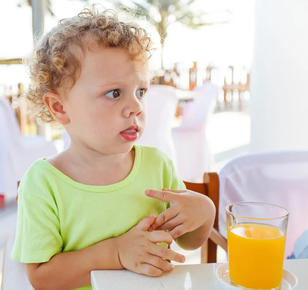 Rapaz bonito beber suco de laranja — Fotografia de Stock