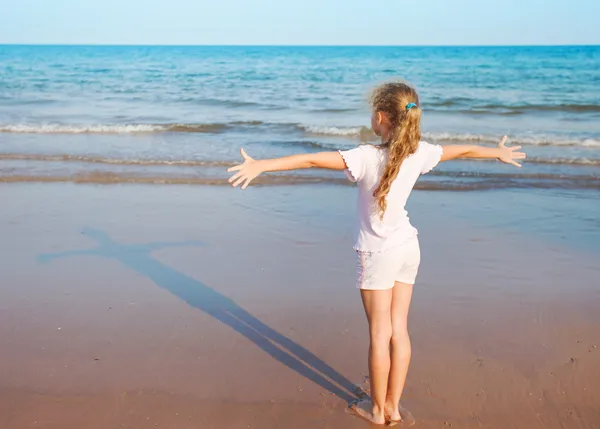 Chica de pie en la playa y mirando su sombra — Foto de Stock