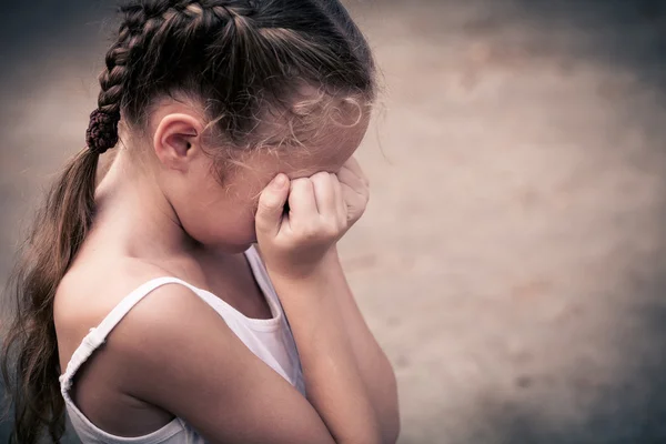 Una mujer triste sentada en el suelo cerca de una pared y sosteniendo su h — Foto de Stock