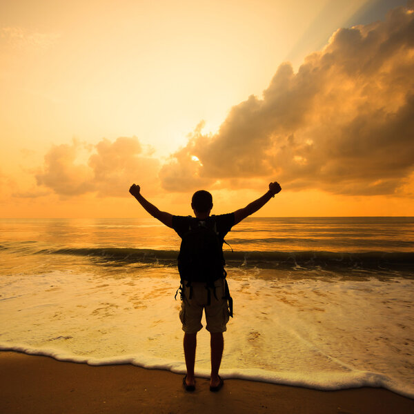 silhouette of a man with a backpack at sunrise on the sea