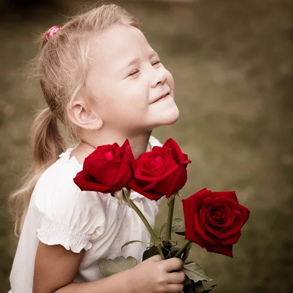 Joyeux enfant avec un bouquet de roses rouges — Photo