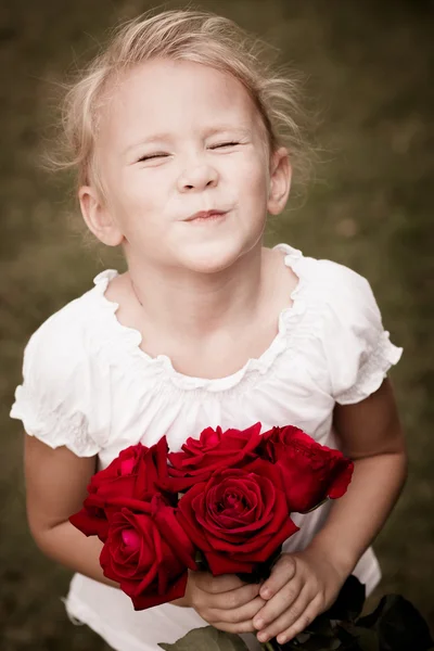 Щаслива дитина з букетом червоних троянд — стокове фото