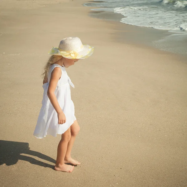 Glückliches kleines Mädchen steht am Strand — Stockfoto