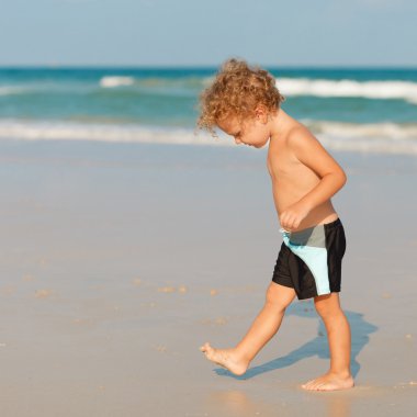 Küçük çocuk kumsalda oynuyor..