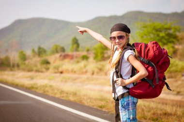 Sırt çantalı küçük kız yolda yürüyor.