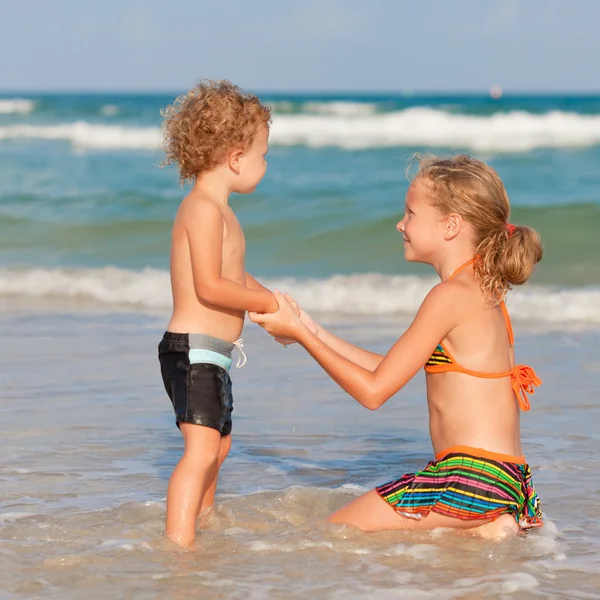 Zwei glückliche Kinder spielen am Strand — Stockfoto