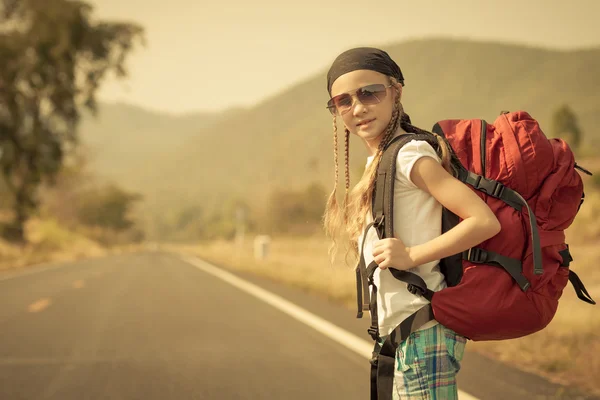 Little girl with backpack walking on the road — Stock Photo, Image