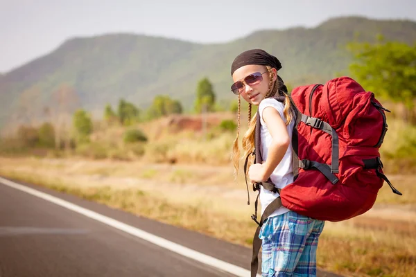 Menina com mochila andando na estrada — Fotografia de Stock