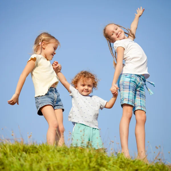 Twee kleine meisjes en kleine jongen dansen op de weg — Stockfoto