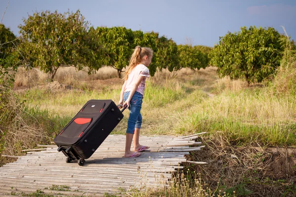 Una bambina con valigia sulla strada — Foto Stock