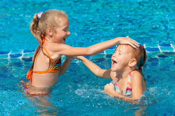 Två glada små flickor leker i poolen Royaltyfria Stockbilder