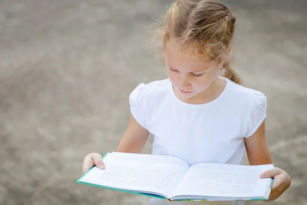 小さな女の子が座って自然界の本を読んで — ストック写真