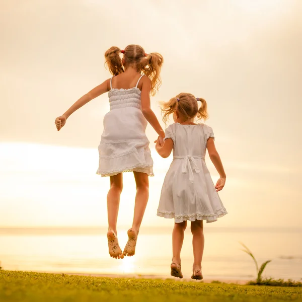 Glückliche Kinder, die im Morgengrauen am Strand springen — Stockfoto