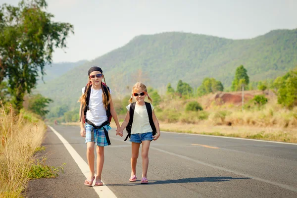 Duas meninas com mochila andando na estrada — Fotografia de Stock