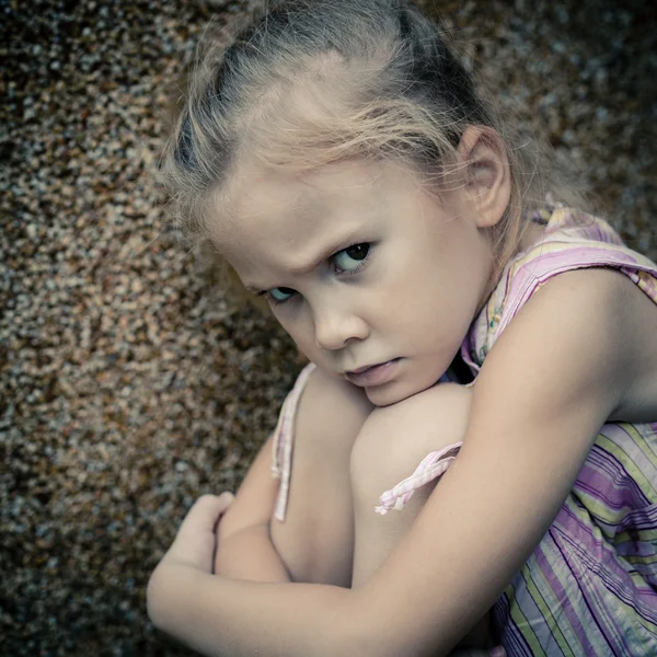 Портрет сумної маленької дівчинки, що сидить біля стіни — стокове фото