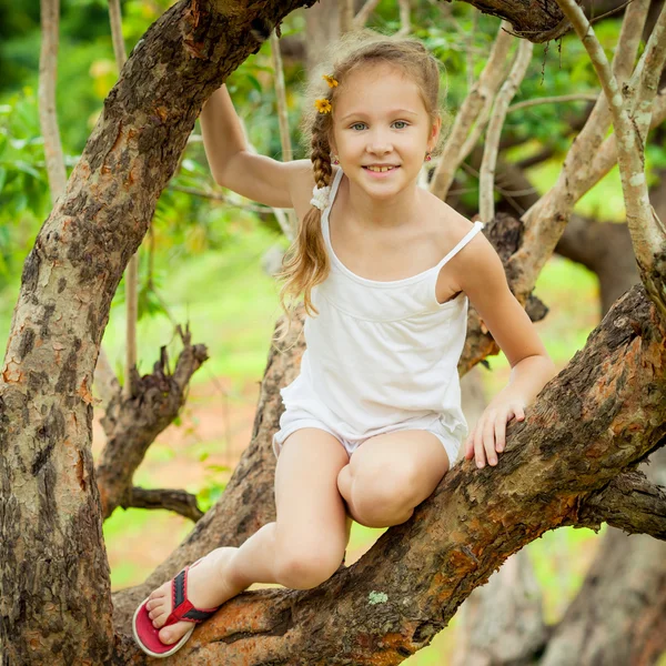 Little girl sitting on the tree — Stock Photo, Image