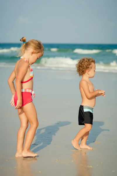 Duas crianças felizes brincando na praia no dia — Fotografia de Stock