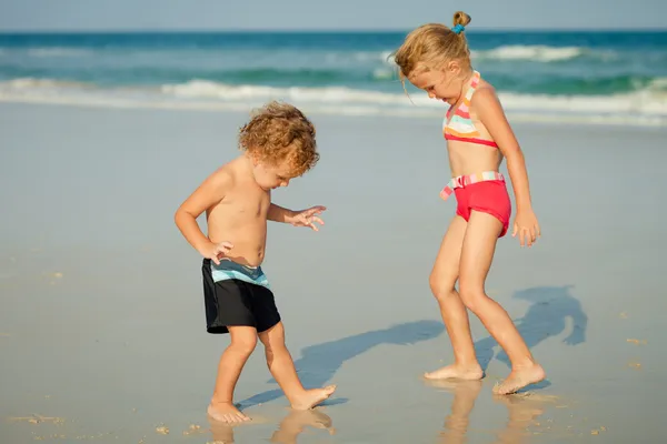 Duas crianças felizes brincando na praia no dia — Fotografia de Stock