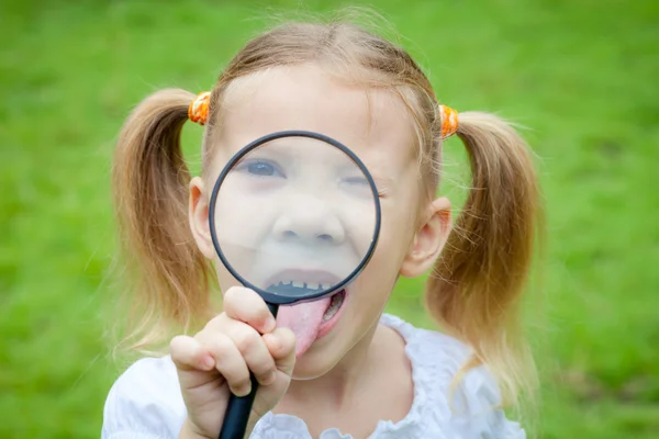 Uma menina com lupa ao ar livre no dia — Fotografia de Stock