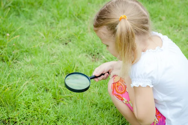 Una niña pequeña con lupa al aire libre durante el día — Foto de Stock