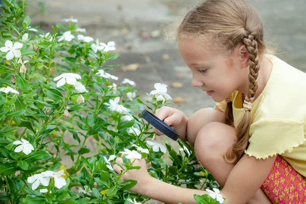 One little girl with magnifying glass outdoors in the day time — Stock Photo, Image