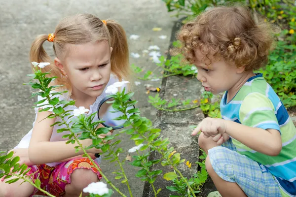 Two little kids with magnifying glass outdoors in the day time — Stock Photo, Image