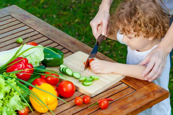 Mother teaches son knife cut cucumber — Stock Photo, Image