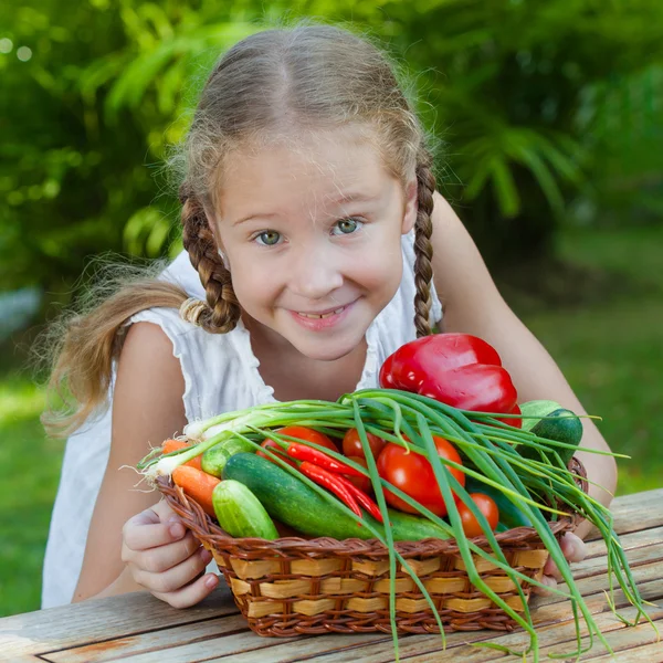 Girl holding a basket of vegetables (cucumber, pepper, tomato, o — Stock Photo, Image