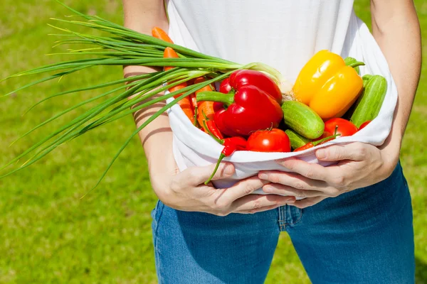 Kvinna med färska grönsaker i knät — Stockfoto