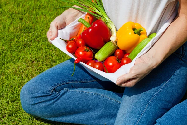 Kvinna med färska grönsaker i knät — Stockfoto