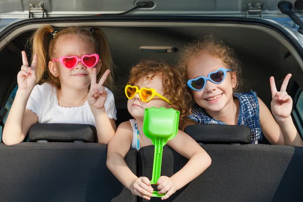 Twee kleine meisjes en jongen zittend in de auto — Stockfoto