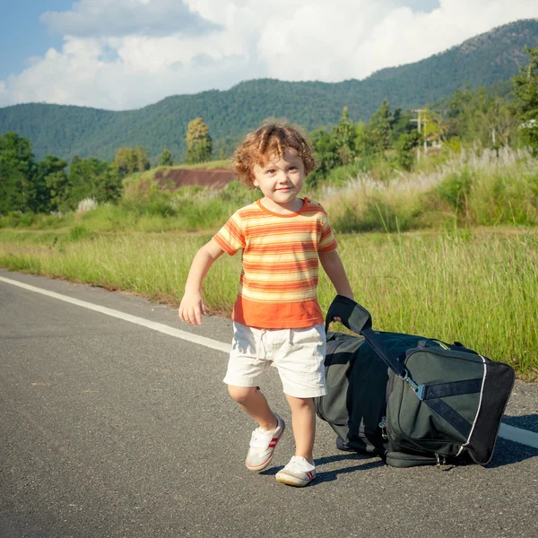 Niño pequeño con una bolsa grande va en el camino durante el día —  Fotos de Stock