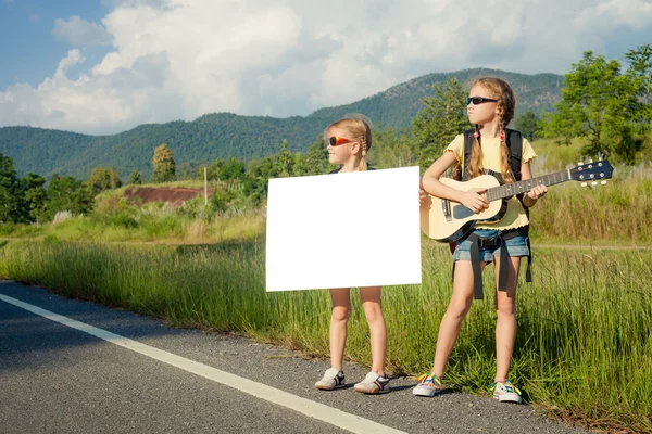 Dos chicas con mochilas de pie en la carretera de la carretera —  Fotos de Stock